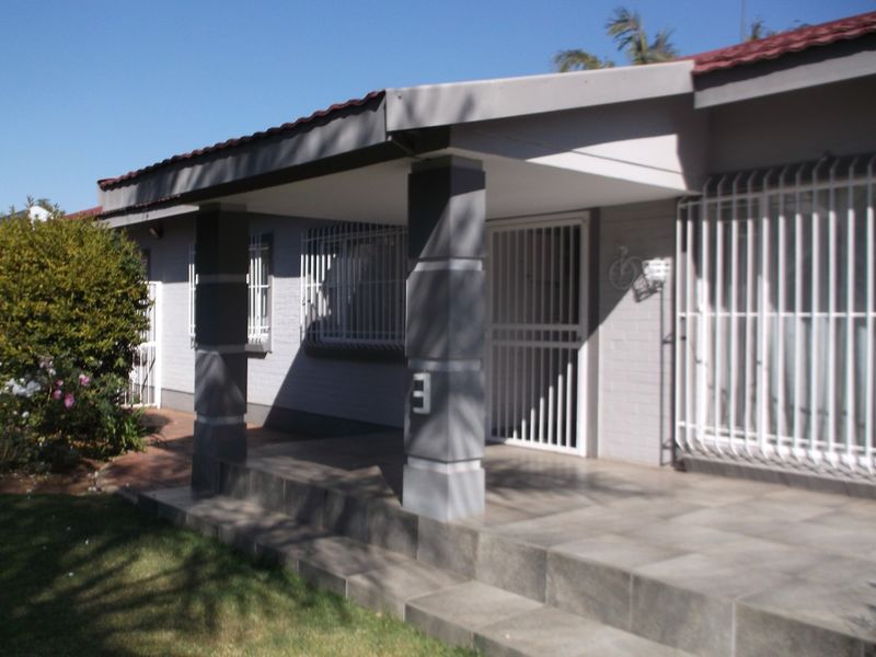 Front entrance of the house featuring a covered tiled patio, security gates, and protective window bars.