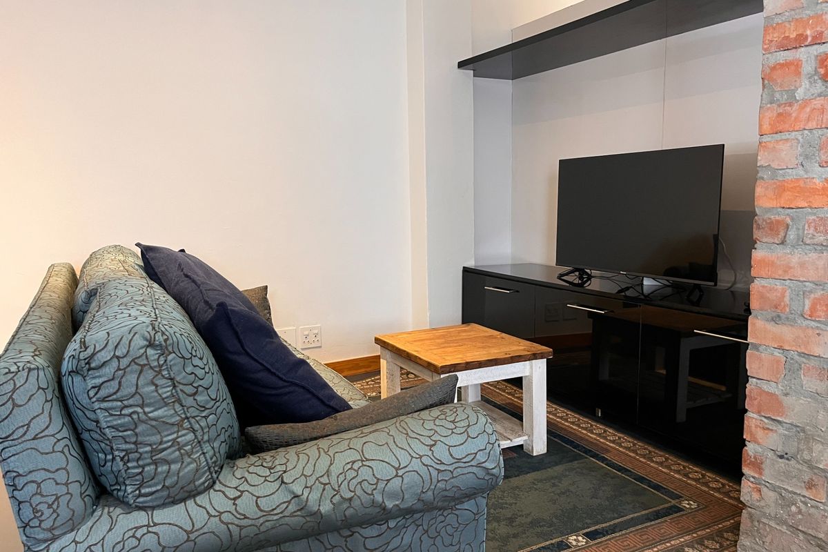 A cozy living room area featuring a distinctive exposed brick column, a sleek built-in media console, and a floating shelf for storage.