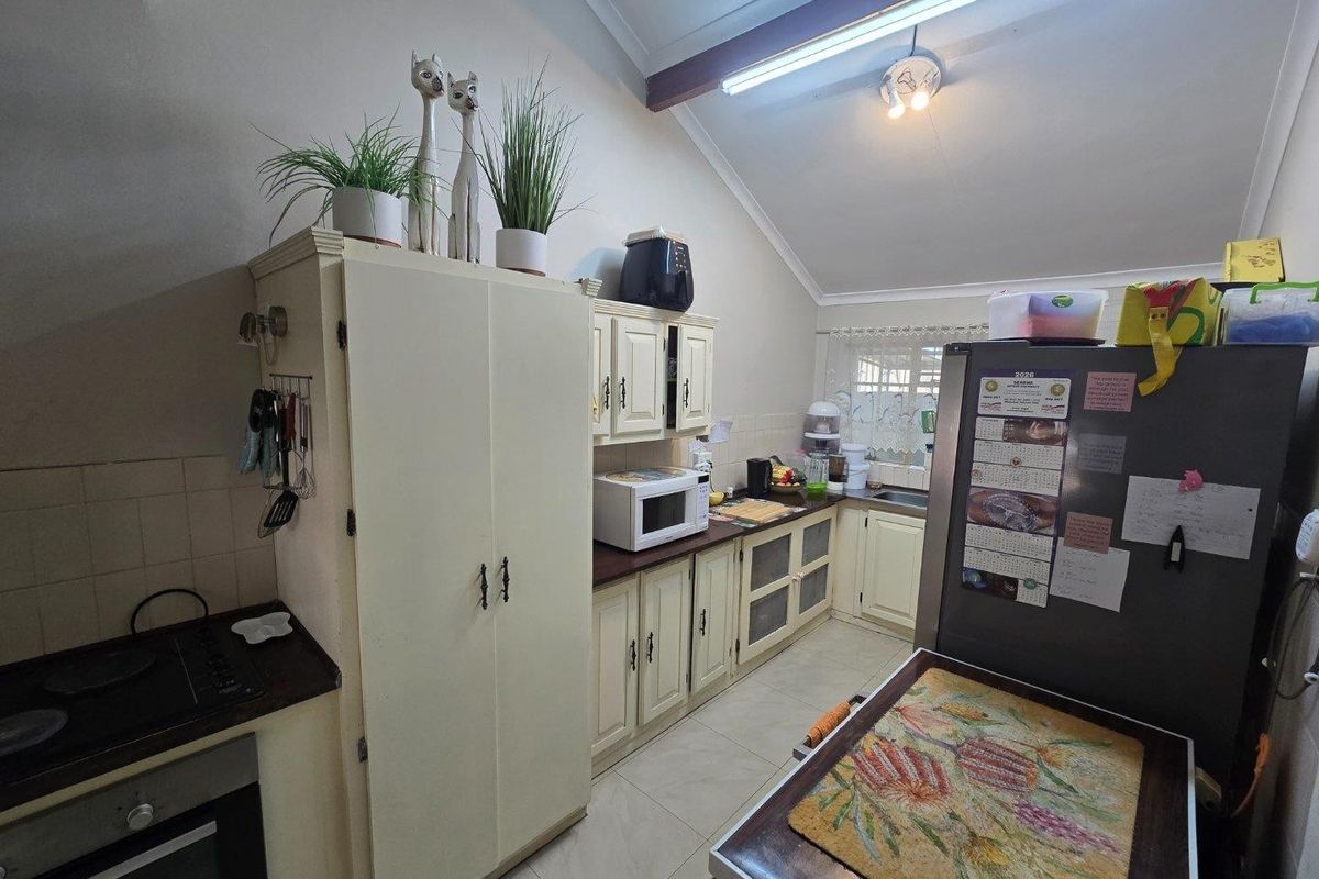 A functional kitchen featuring built-in cabinetry, laminate countertops, an electric hob, and a built-in oven under a vaulted ceiling with tiled flooring.