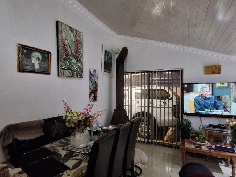Living room featuring tiled flooring, a wood-burning fireplace, and a sliding glass door with security gate access.