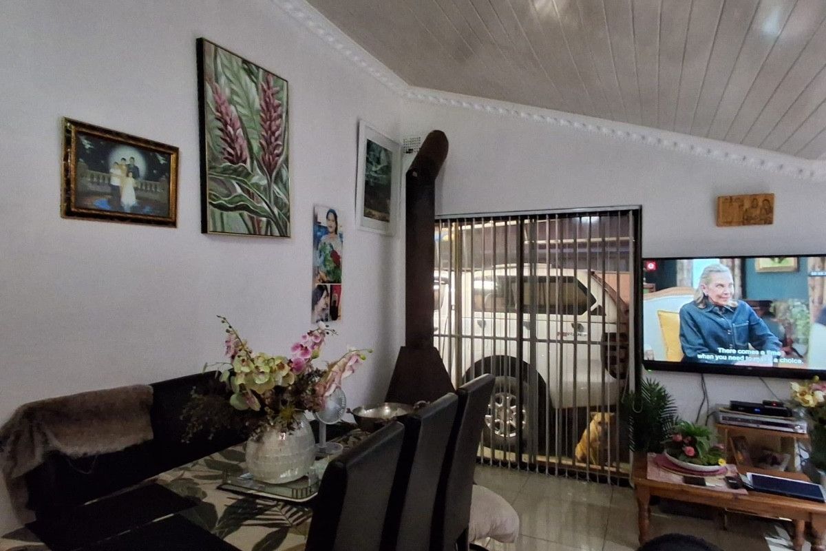 Living room featuring tiled flooring, a wood-burning fireplace, and a sliding glass door with security gate access.