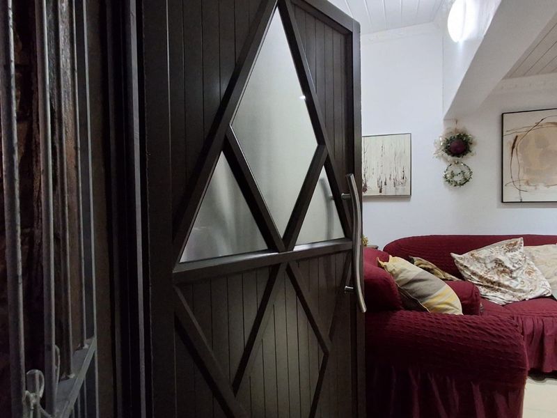 A view of the interior entrance featuring a custom dark timber door with geometric frosted glass panels and a high-set tongue and groove ceiling.