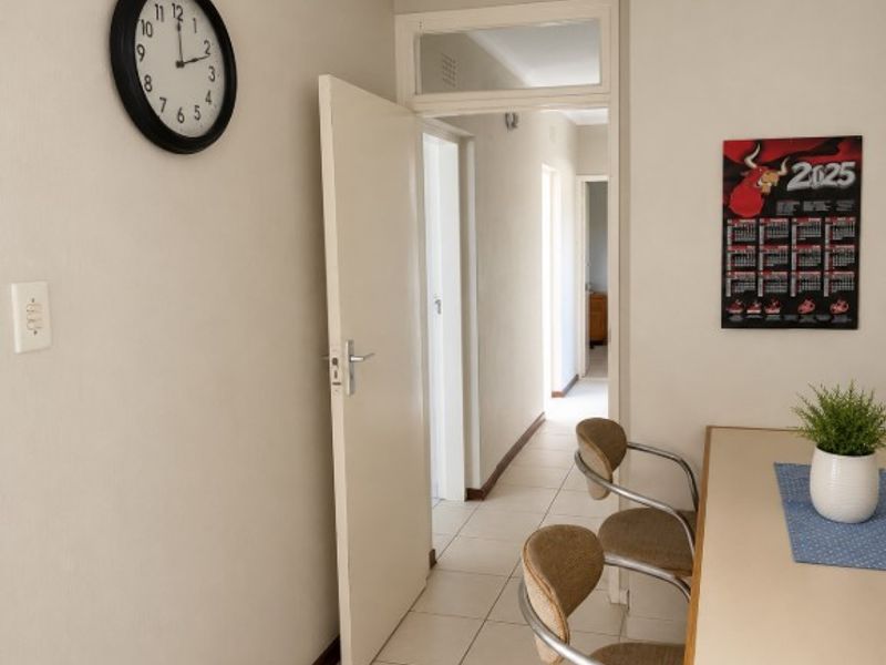 A functional hallway featuring tiled flooring and a transom window above the internal door, providing access to adjacent rooms within the apartment.