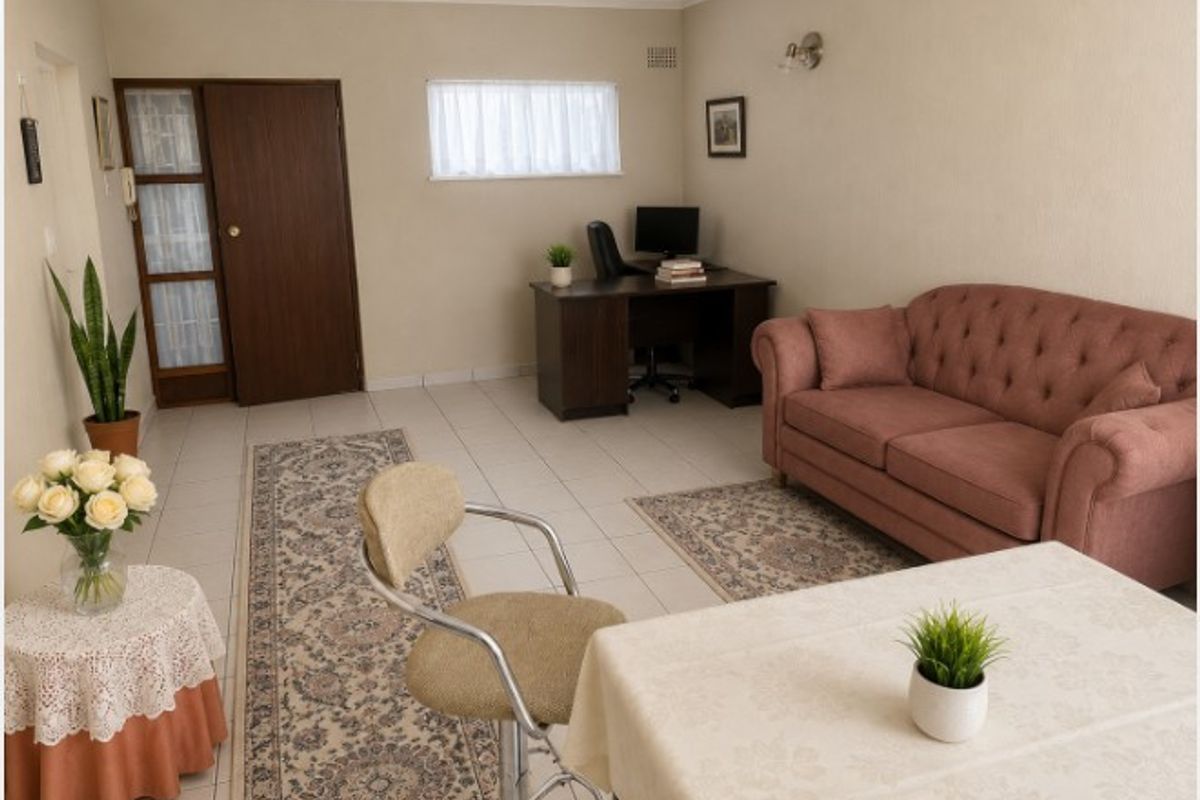 A spacious living area featuring neutral wall tones, tiled flooring, and a functional layout suitable for a combined lounge and home office setup.