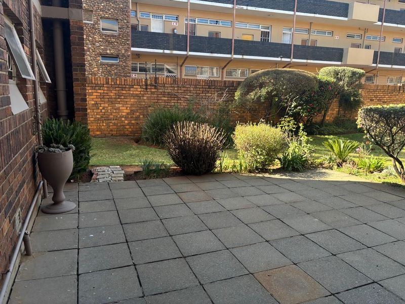 A private rear patio area featuring paved flooring and a landscaped garden enclosed by a brick boundary wall.