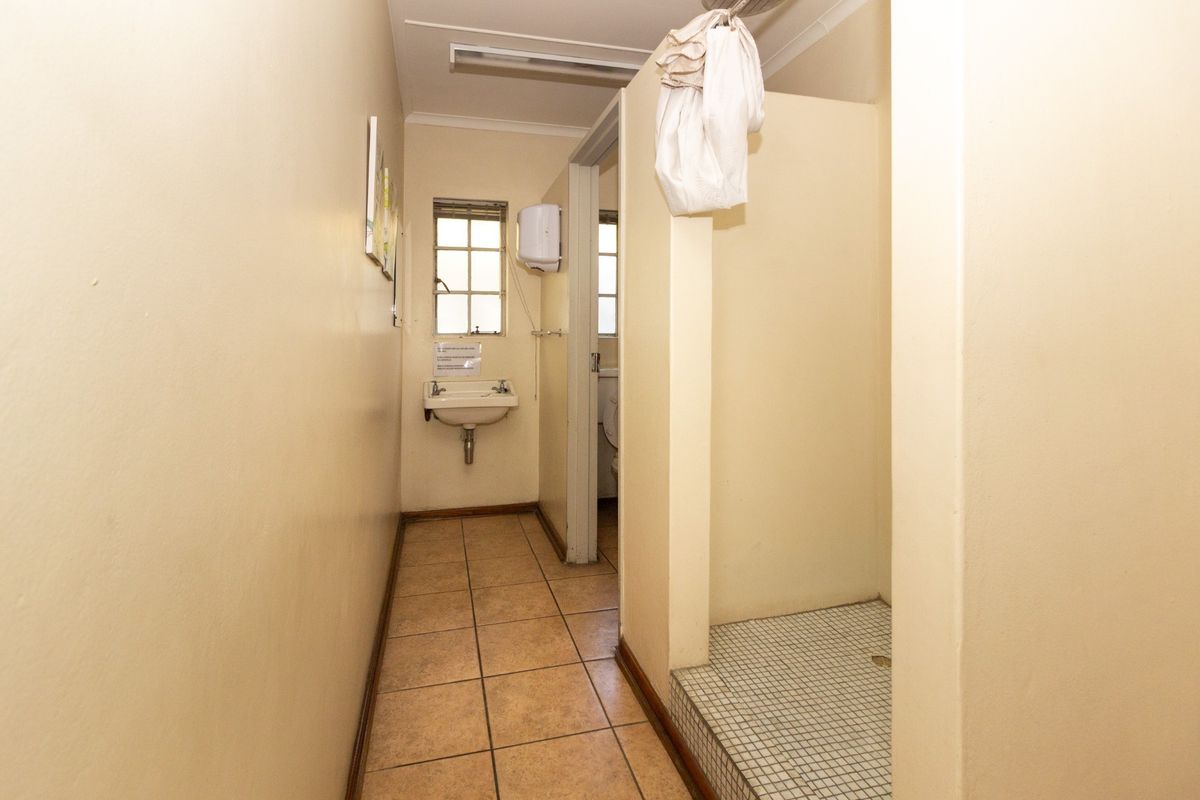 A functional industrial-style bathroom featuring a wall-mounted basin, tiled flooring, and a dedicated shower area.