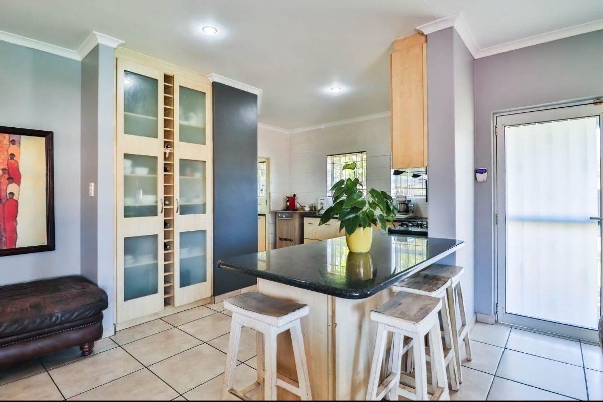 A functional kitchen featuring a central island with a granite countertop, ample built-in cabinetry, and tiled flooring, providing a practical and well-lit workspace.