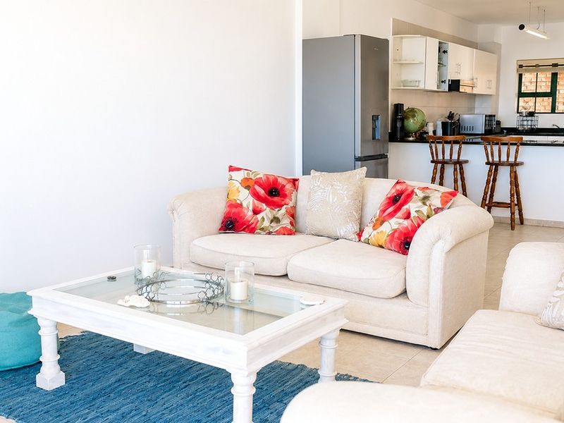Open-plan living area featuring a functional kitchen with granite countertops and a breakfast bar, seamlessly connected to the lounge space.