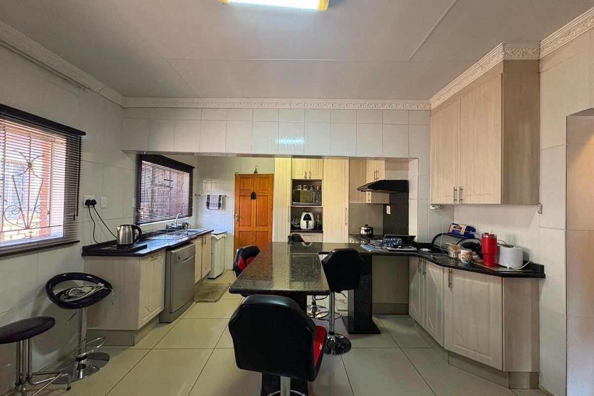 Spacious kitchen featuring granite countertops, built-in cabinetry, and a central breakfast bar, offering a functional layout with ample storage and workspace.