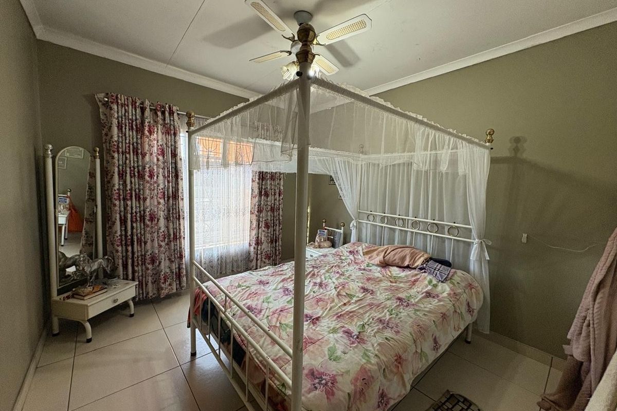 A bedroom featuring tiled flooring, a ceiling fan, and neutral wall tones, offering a functional space ready for modern updates.