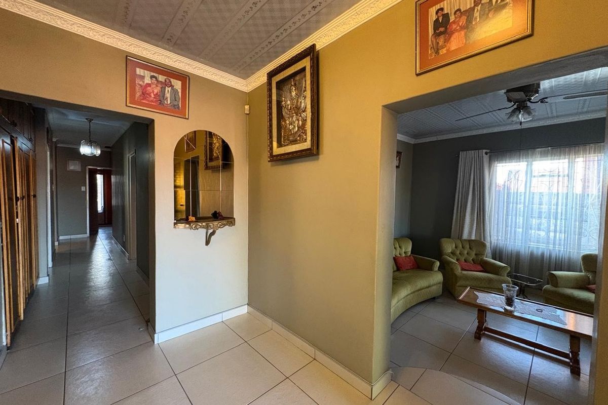 A living room area featuring tiled flooring, decorative ceiling tiles, and an open archway leading to an adjacent space.