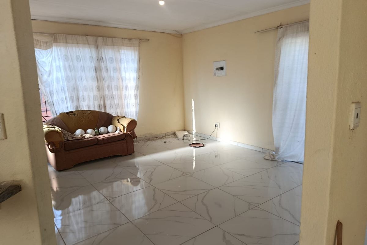 A living room featuring large format marble-look floor tiles and neutral wall tones, offering a blank canvas for interior design updates.