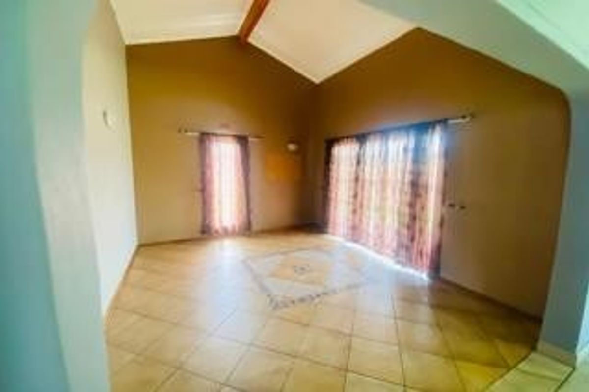 Spacious living room featuring vaulted ceilings, ceramic tile flooring, and large sliding glass doors providing natural light and access to the outdoors.