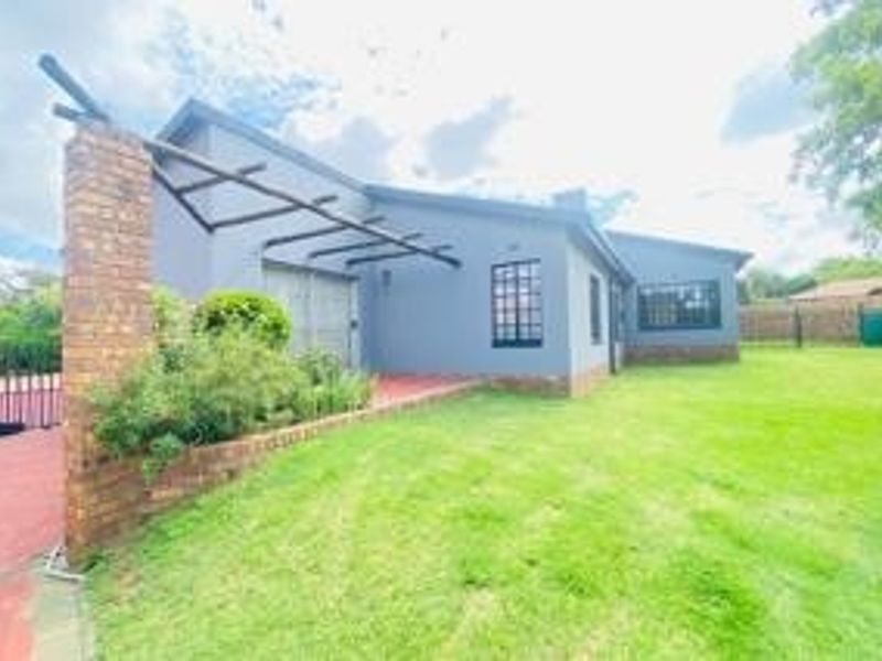 Rear view of the property featuring a paved patio area, timber pergola, and a spacious garden with established lawn.