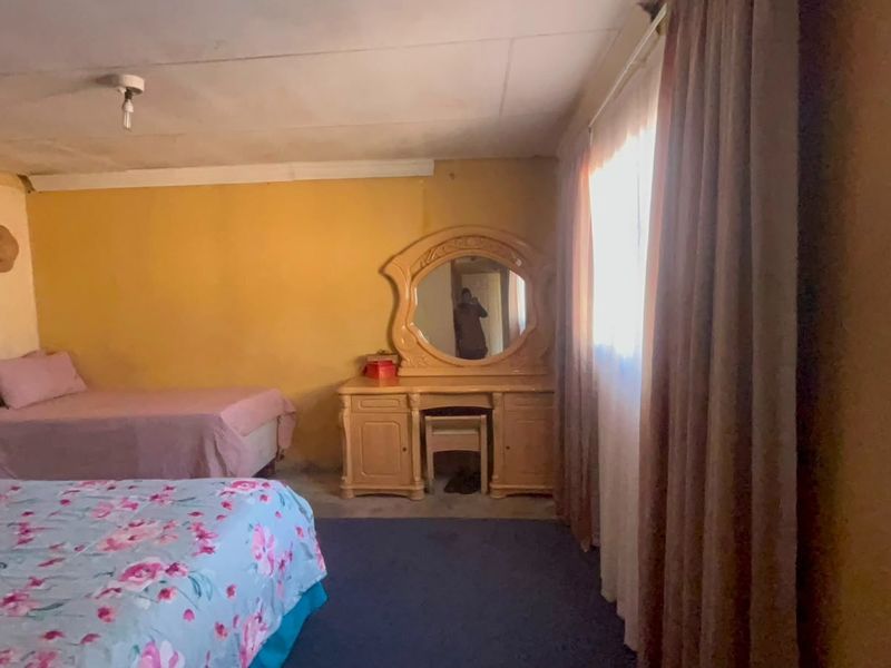 A bedroom featuring dated wall finishes and ceiling condition, requiring cosmetic updates to improve the overall aesthetic and appeal.