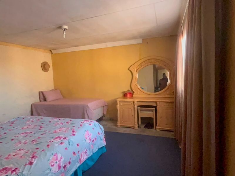 A bedroom featuring basic finishes, requiring cosmetic updates to the walls and ceiling to improve the overall aesthetic and condition.