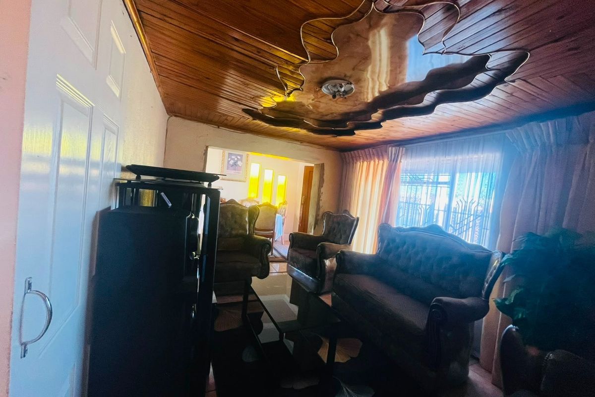 A living room featuring a timber-clad ceiling with a decorative central feature and access to an adjoining space.