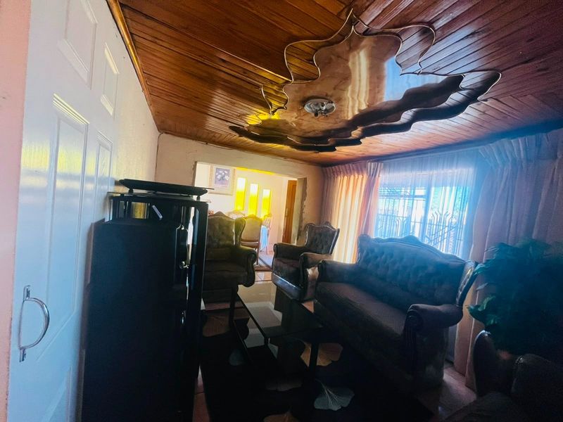 A living room featuring a timber-clad ceiling with a decorative central feature and access to an adjoining space.