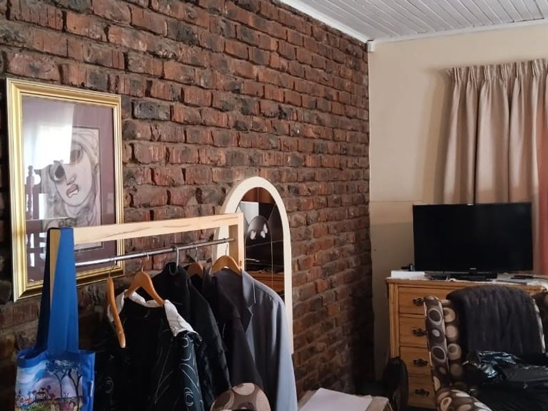 A bedroom featuring a rustic exposed brick feature wall and a white timber panel ceiling, offering a characterful foundation for interior updates.