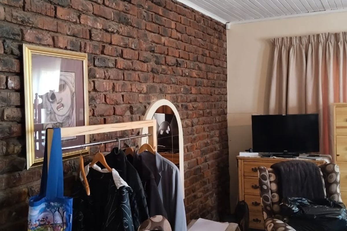 A bedroom featuring a rustic exposed brick feature wall and a white timber panel ceiling, offering a characterful foundation for interior updates.