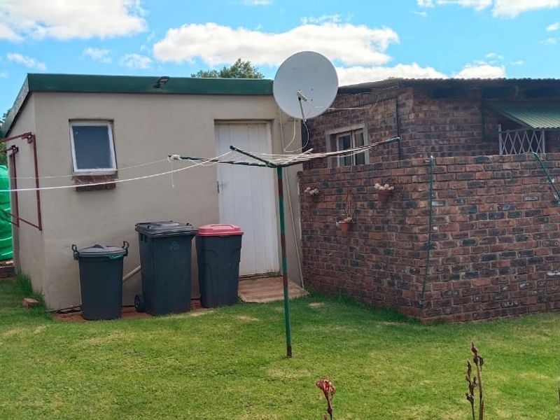Rear exterior view of the property featuring a brick wall, water storage tank, and utility area with a satellite dish.