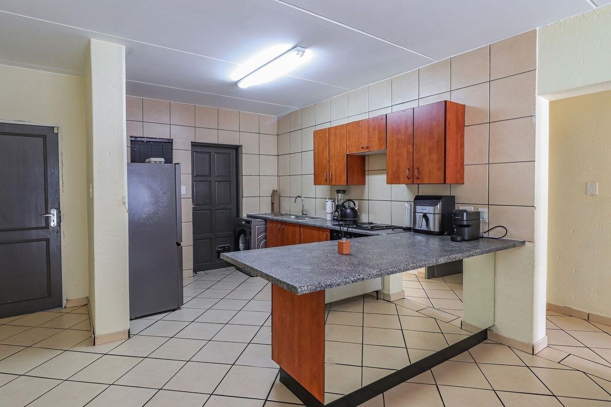 Functional kitchen featuring built-in wooden cabinetry, granite countertops with a breakfast bar, tiled backsplash, and integrated hob, offering a practical layout for daily use.