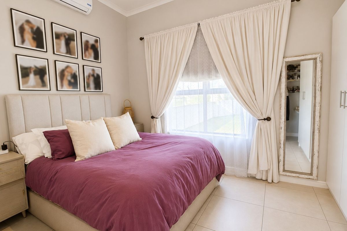 A well-maintained bedroom featuring tiled flooring, a split-system air conditioner, and a built-in wardrobe with a view of the garden.