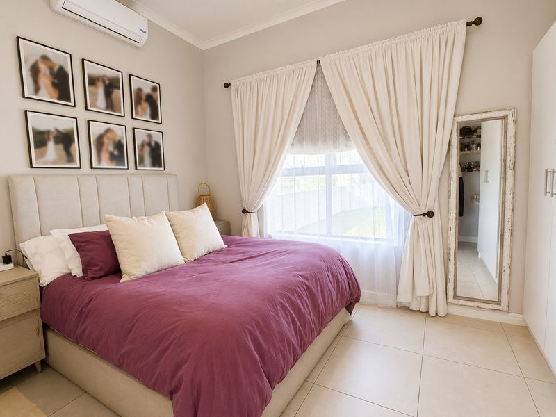 A well-maintained bedroom featuring tiled flooring, a split-system air conditioner, and a built-in wardrobe with a view of the garden.