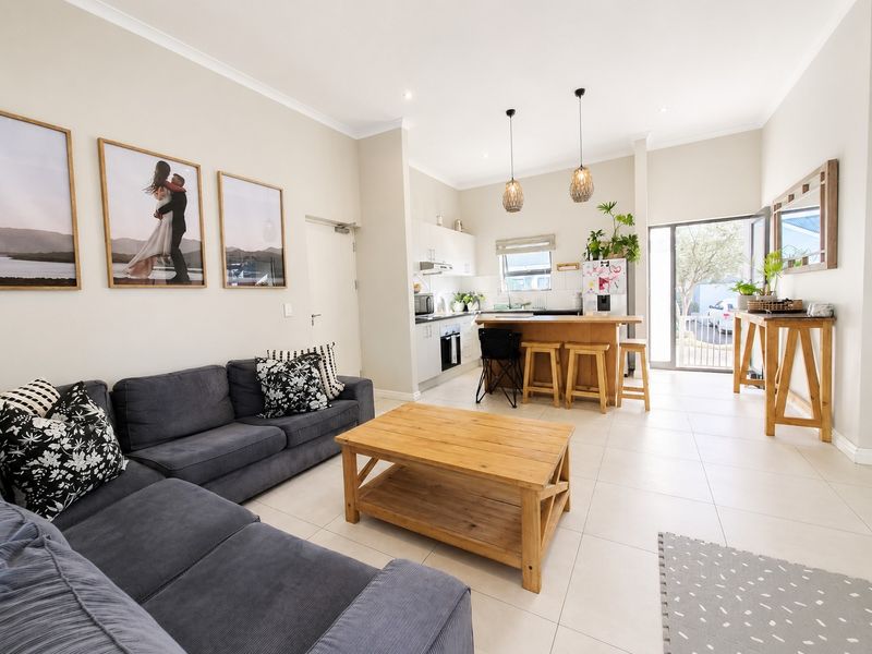 Open-plan living and kitchen area featuring tiled floors, modern cabinetry, a central kitchen island, and direct access to the exterior.