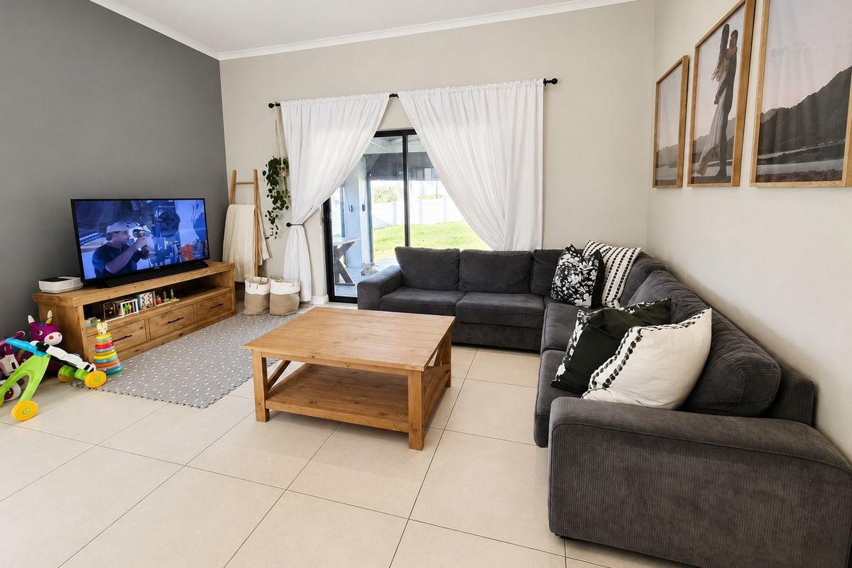 A bright and well-maintained living room featuring large format floor tiles, a feature wall, and sliding glass doors providing access to the outdoor area.