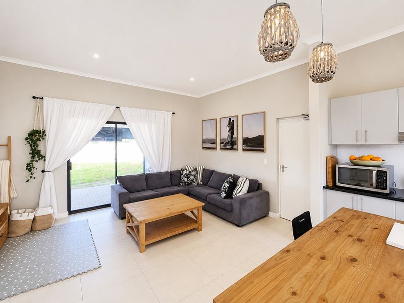 Bright open-plan living area featuring tiled floors, modern pendant lighting, and a sliding glass door providing direct access to the rear patio.