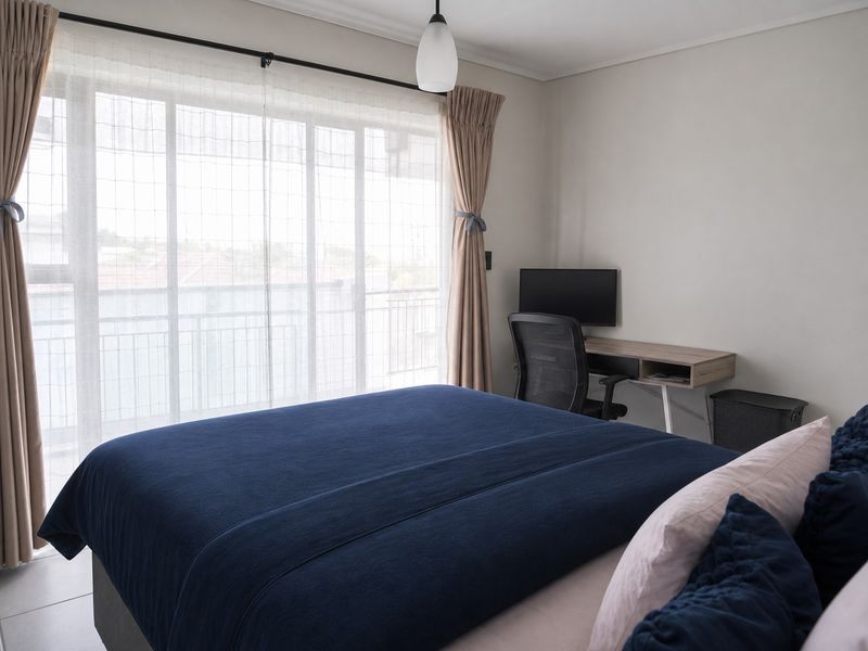 A well-lit bedroom featuring tiled flooring and a large sliding glass door that provides access to an outdoor balcony area.