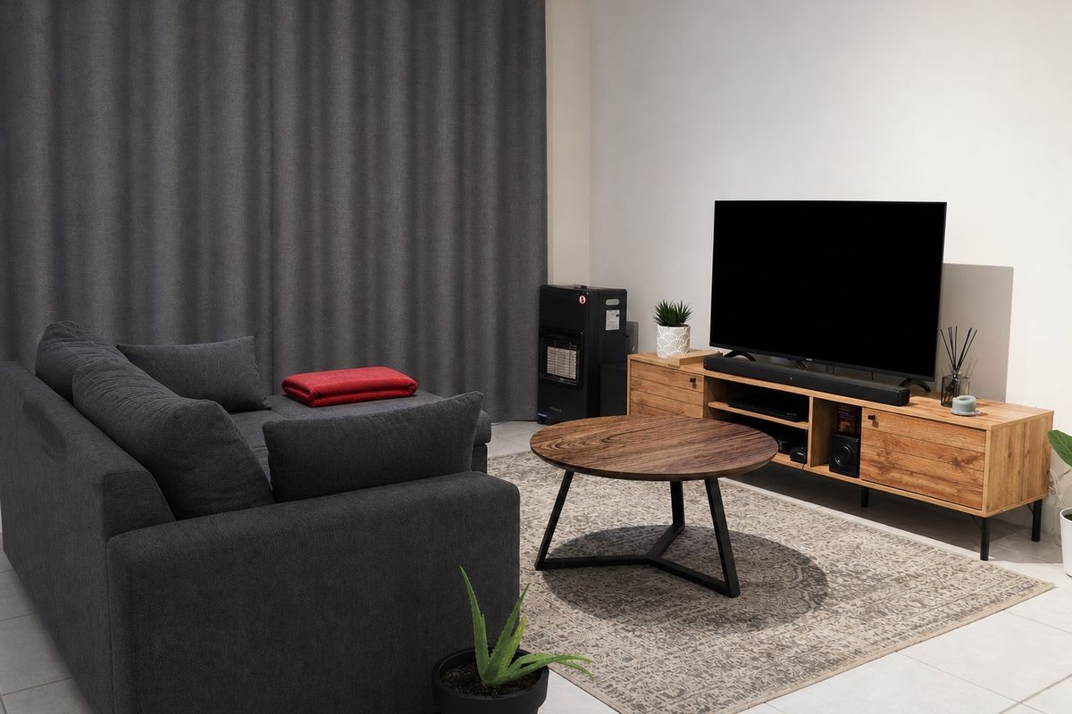 A well-maintained living room featuring neutral tiled flooring and full-length curtains, providing a clean and functional space.