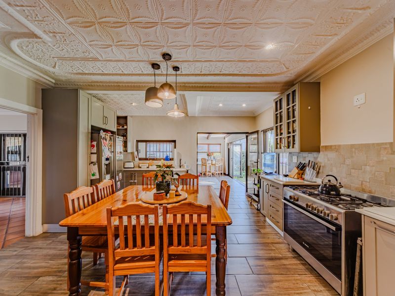 Spacious open-plan kitchen and dining area featuring a gas stove, built-in cabinetry, tiled flooring, and a decorative pressed metal ceiling.