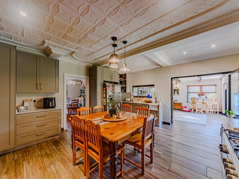 Spacious open-plan kitchen and dining area featuring elegant pressed metal ceilings, modern tiled flooring, and custom cabinetry with integrated appliances.