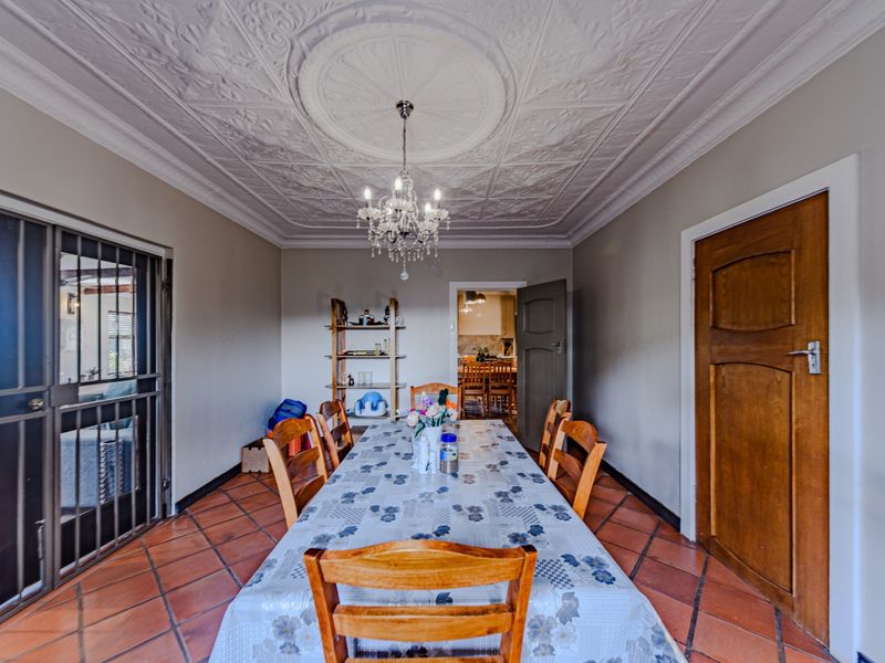 Dining room featuring a decorative pressed metal ceiling with a central rose, terracotta floor tiles, and access to an adjoining kitchen area.