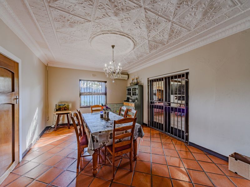 Dining room featuring traditional terracotta floor tiles, an ornate pressed metal ceiling, and a secure metal gate leading to an adjacent space.