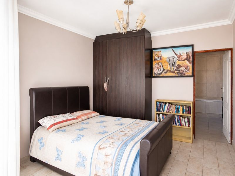 A well-maintained bedroom featuring tiled flooring, a built-in dark wood wardrobe, and direct access to an en-suite bathroom.