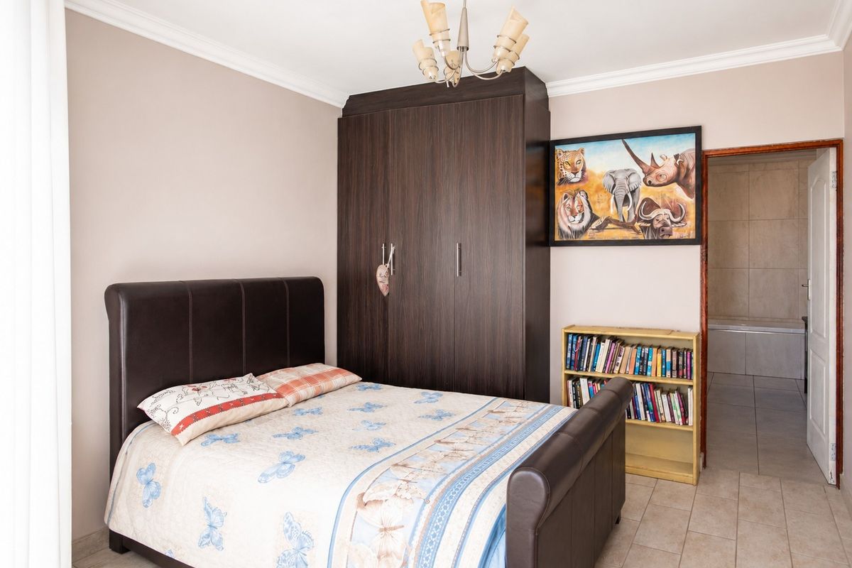 A well-maintained bedroom featuring tiled flooring, a built-in dark wood wardrobe, and direct access to an en-suite bathroom.