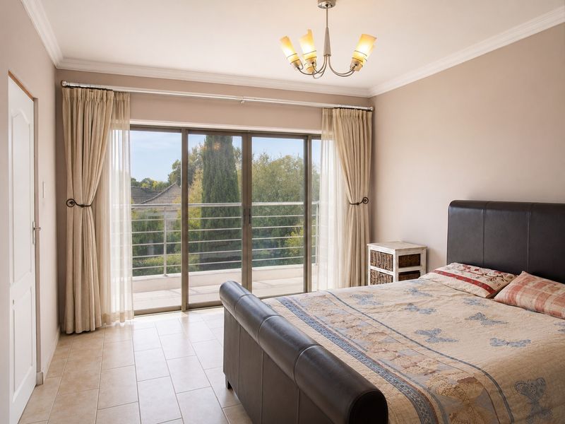 Spacious bedroom featuring tiled flooring, ceiling cornice, and large sliding glass doors opening onto a private balcony with scenic views.