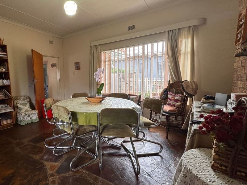 Dining room featuring unique stone flooring and a brick fireplace, with large windows fitted with security bars.