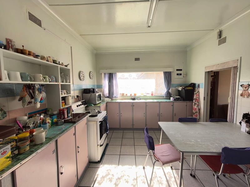A dated kitchen featuring original cabinetry, tiled flooring, and a freestanding stove, offering significant potential for a modern renovation.