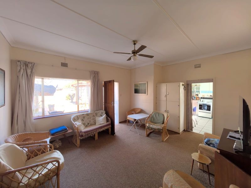 A spacious living room featuring a ceiling fan, built-in storage, and large windows, providing a functional base for renovation and modernization.