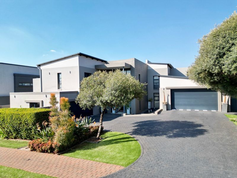 Modern double-story residential property featuring a paved driveway, double garage, and well-maintained landscaped front garden.