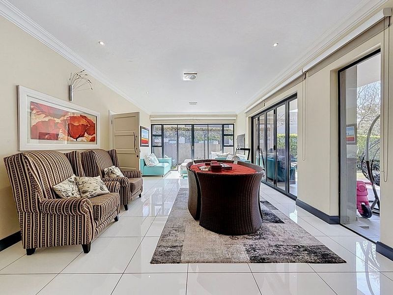 Spacious living area featuring polished tiled flooring, recessed downlighting, and large aluminium stacker doors providing seamless access to the outdoor patio area.