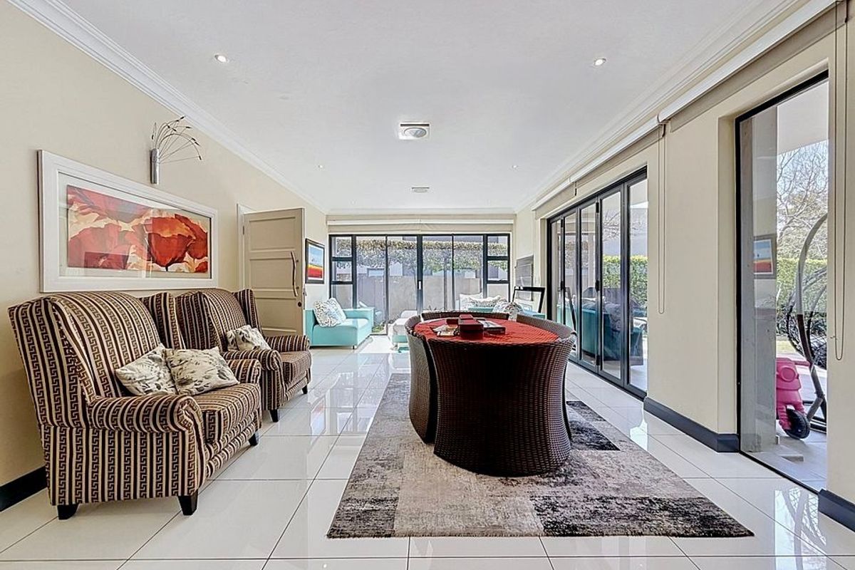 Spacious living area featuring polished tiled flooring, recessed downlighting, and large aluminium stacker doors providing seamless access to the outdoor patio area.