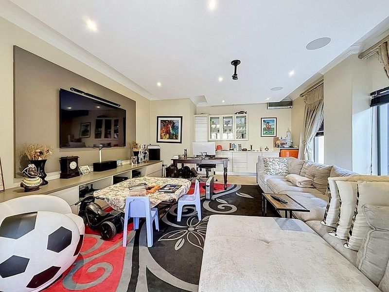 Spacious living room featuring built-in cabinetry, recessed downlighting, ceiling speakers, and a wall-mounted air conditioning unit.
