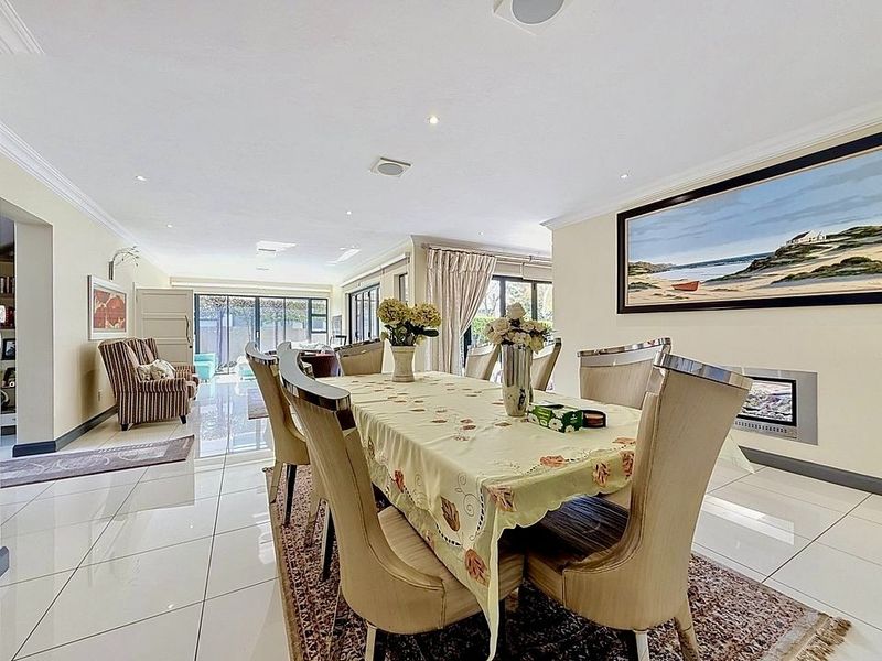 Spacious dining area featuring polished tiled flooring, recessed downlighting, and a modern built-in fireplace, with seamless access to the outdoor patio through sliding doors.