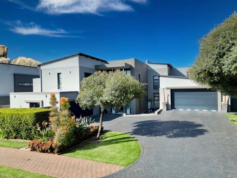 A modern double-story residence featuring a paved driveway, double garage, and well-maintained landscaped garden with a contemporary architectural facade.