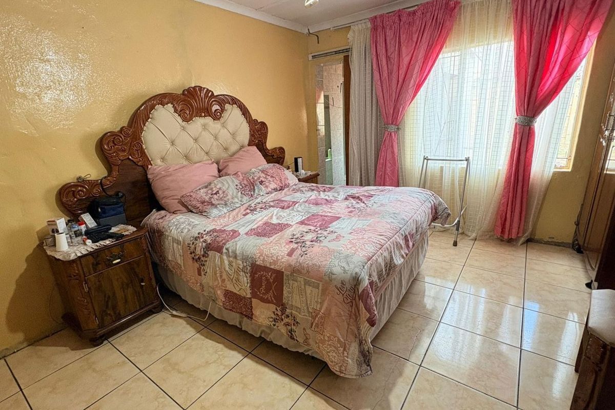 A bedroom featuring tiled flooring and a sliding door, requiring cosmetic updates to improve the overall aesthetic and condition of the space.